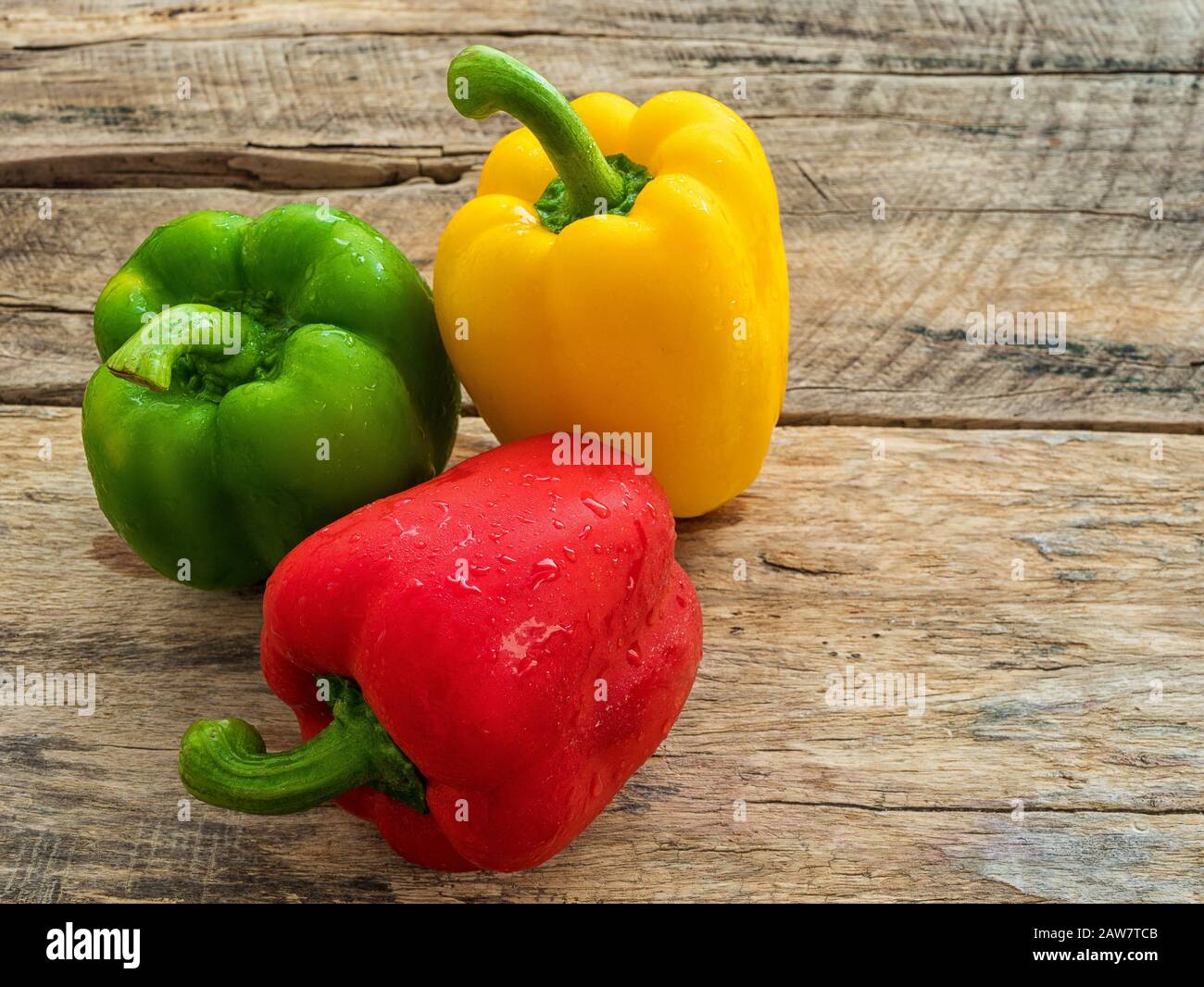 peperone verde fresco, rosso e giallo su sfondo ligneo, spezie vegetali Foto Stock