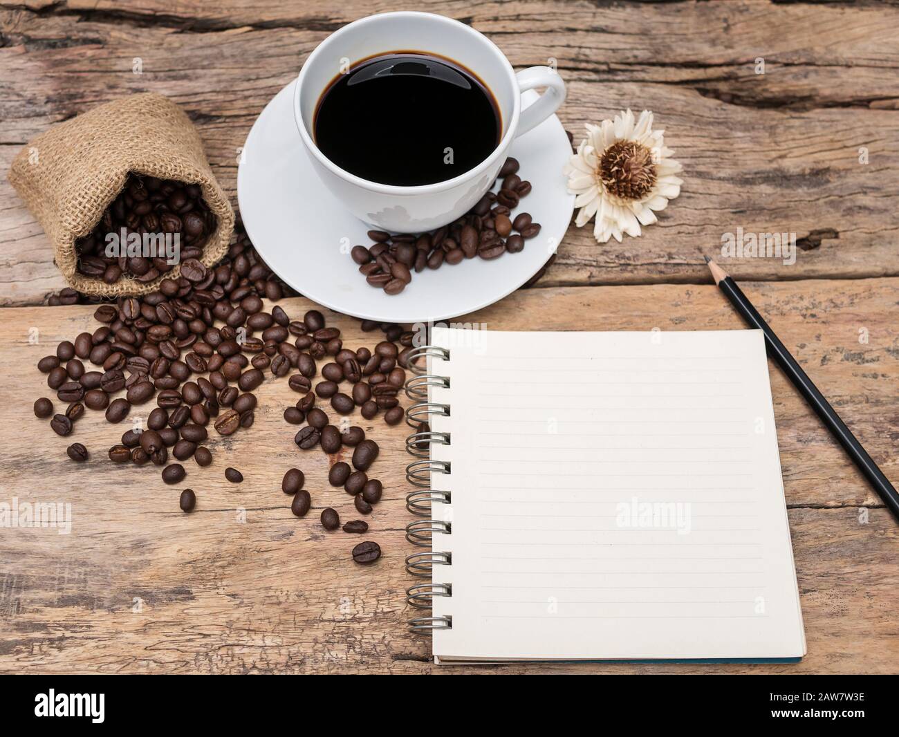 caffè caldo con chicchi di caffè e taccuino su tavola di legno. menu di fondo caffè per caffetteria o caffetteria, ricetta per barista. Foto Stock