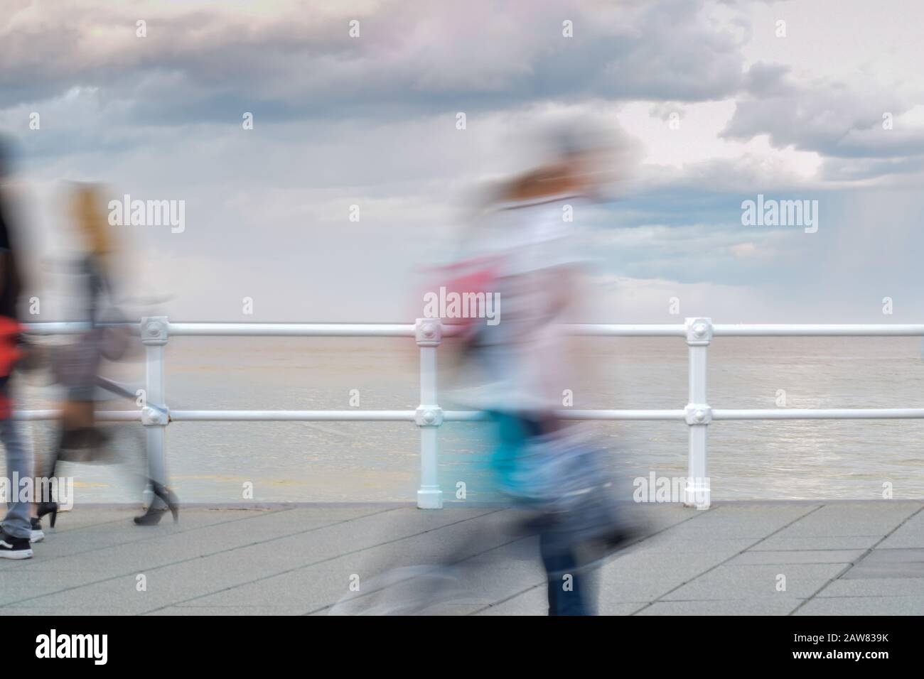 Persone anonime che camminano di fronte al mare. Concetto di movimento. Scena offuscata . Foto Stock