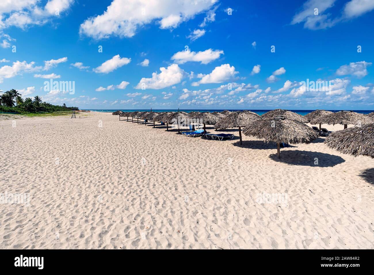 ampia spiaggia di sabbia con lettini e ombrelloni sullo sfondo del mare blu Foto Stock