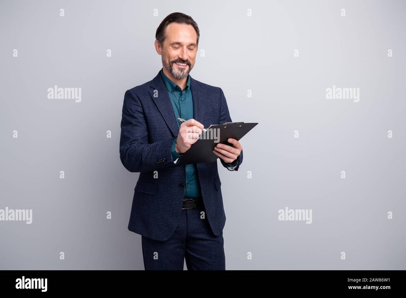 Foto di buon umore business manager uomo tenere contratto aziendale appunti firma penna dettagli finali accordo formalwear blazer camicia pantaloni blu vestito Foto Stock