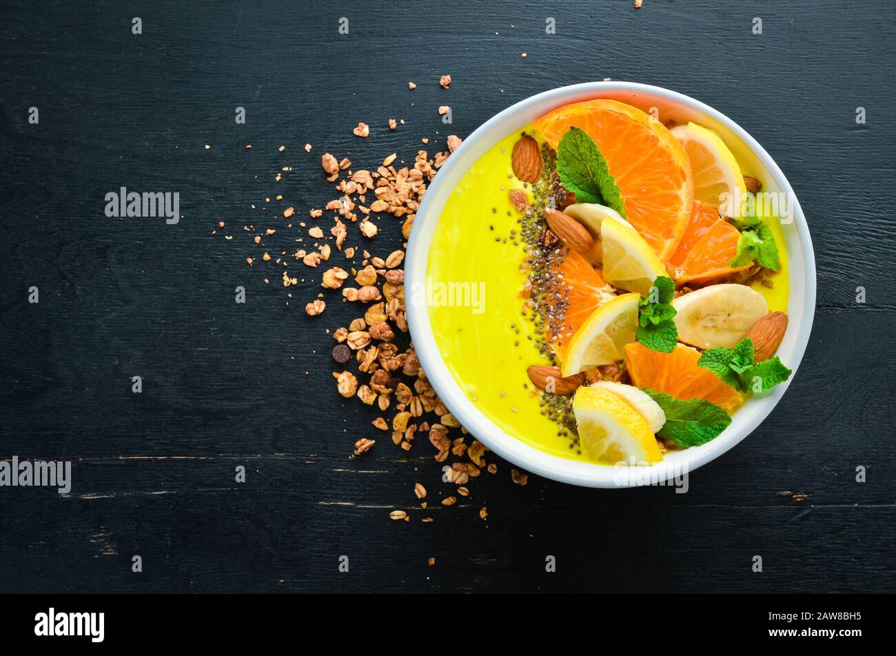 Ciotola per frullato con arancia, banana, limone e mandorle. Colazione. Vista dall'alto. Spazio libero per il testo. Foto Stock