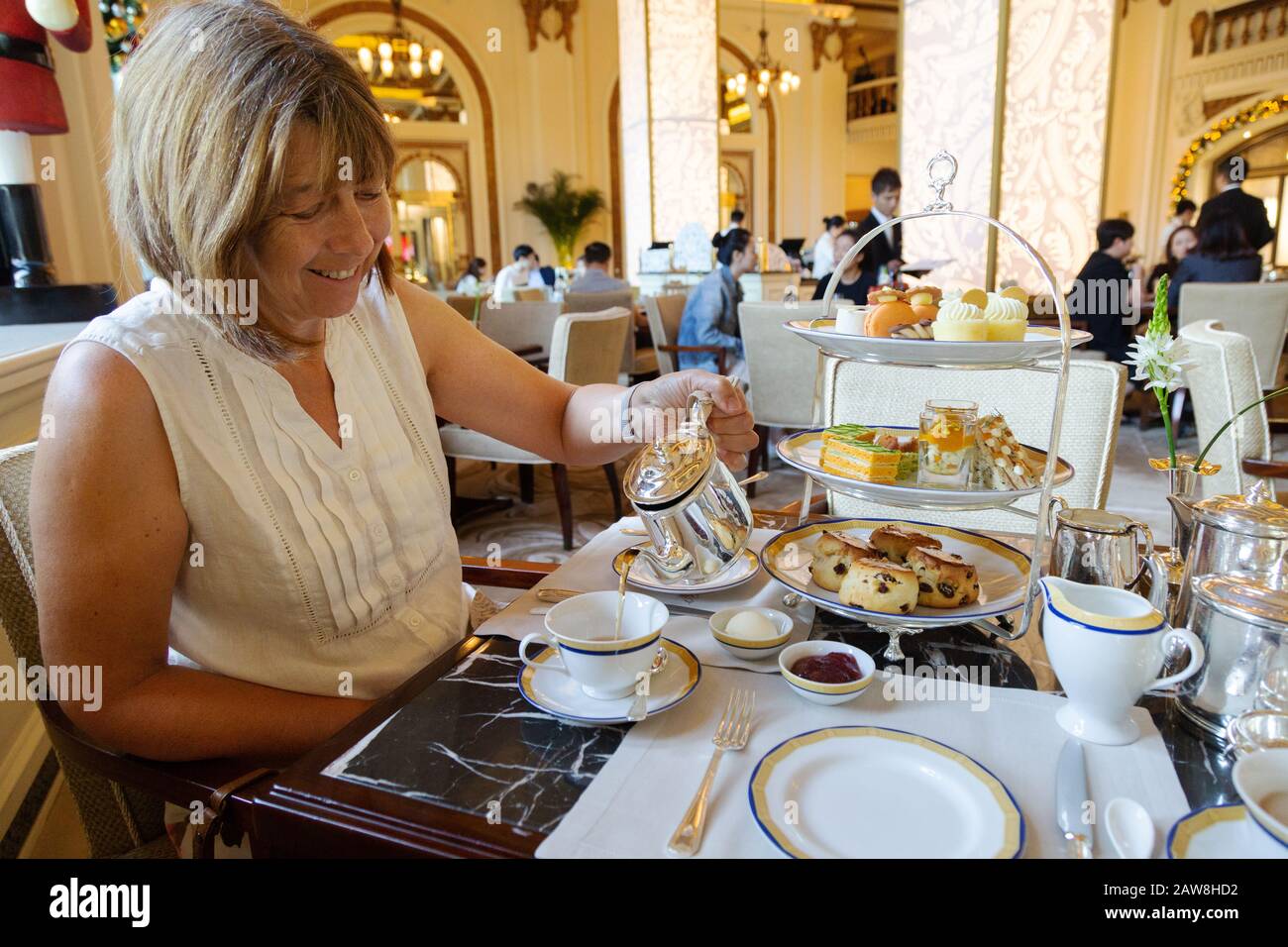 Una donna caucasica di mezza età che ha tè pomeridiano, il Peninsula hotel, Hong Kong Asia Foto Stock
