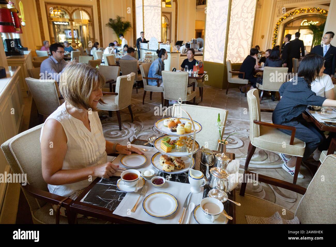 Una donna caucasica di mezza età turistica che ha tè pomeridiano, l'hotel Peninsula, Hong Kong Asia Foto Stock
