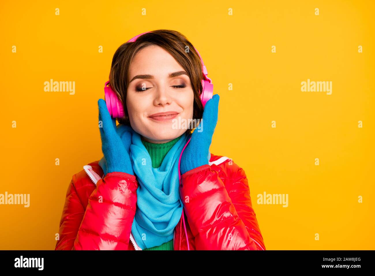 Closeup foto di bella signora occhi chiusi ascoltare auricolari moderni canzoni romantiche parole indossare elegante casual rosso cappotto blu sciarpa guanti isolati Foto Stock