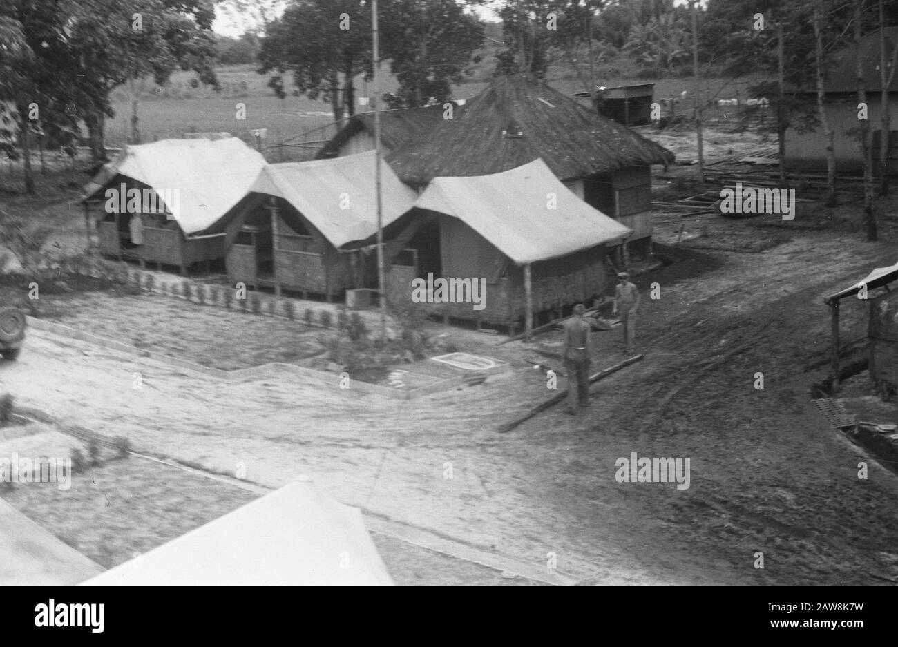 Foto da articoli artiglieria fa storia e Alloggio nella giungla nella rivista Wapenbroeders Marihat. Artiglieria Dell'Esercito Del Bivacco. Tre cabine con tela. Due soldati in un parco con un flagpole e un'immagine della parte [5-11 R.I.] stanno lavorando alla configurazione dei poli telefonici Annotation: Marihat? Buntu Turunan? (Simalungun Nord Sumatra). Il reggimento è di 5-11 R.I. Date: 14 Novembre 1948 Location: Indonesia Dutch East Indies Foto Stock
