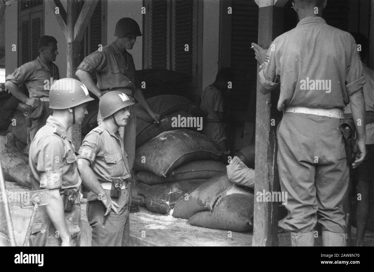 Rembang, Blora e Tjepoe [poliziotti militari in piedi da una pila di balle su un portico] Data: 10 gennaio 1949 luogo: Indonesia, Java, India olandese Foto Stock