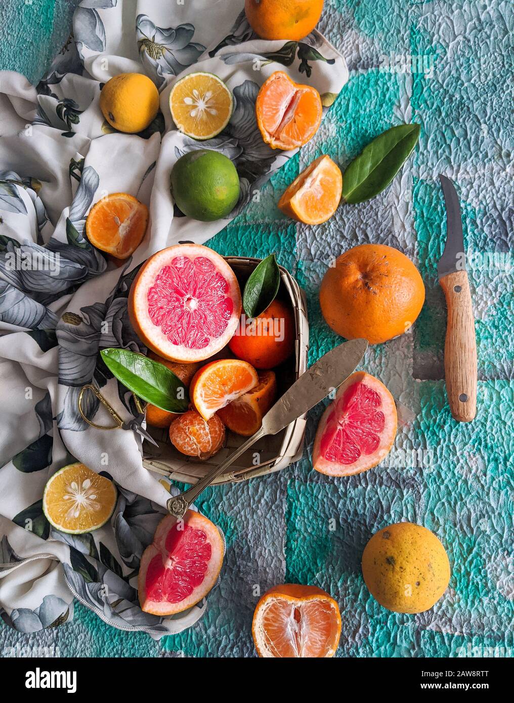 Assortimento di agrumi, a fette, con un coltello su fondo blu. Frutti tropicali misti, lime, limone, arancia, estate, fresco, biologico, fattoria, caffè Foto Stock