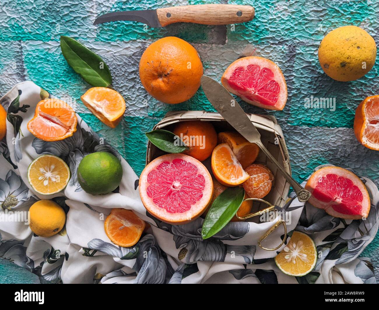 Assortimento di agrumi, a fette, con un coltello su fondo blu. Frutti tropicali misti, lime, limone, arancia, estate, fresco, biologico, fattoria, caffè Foto Stock