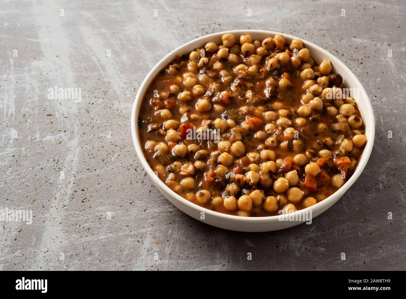 un piatto con uno stufato di ceci vegetariano con alghe kombu, su una superficie grigia rustica Foto Stock