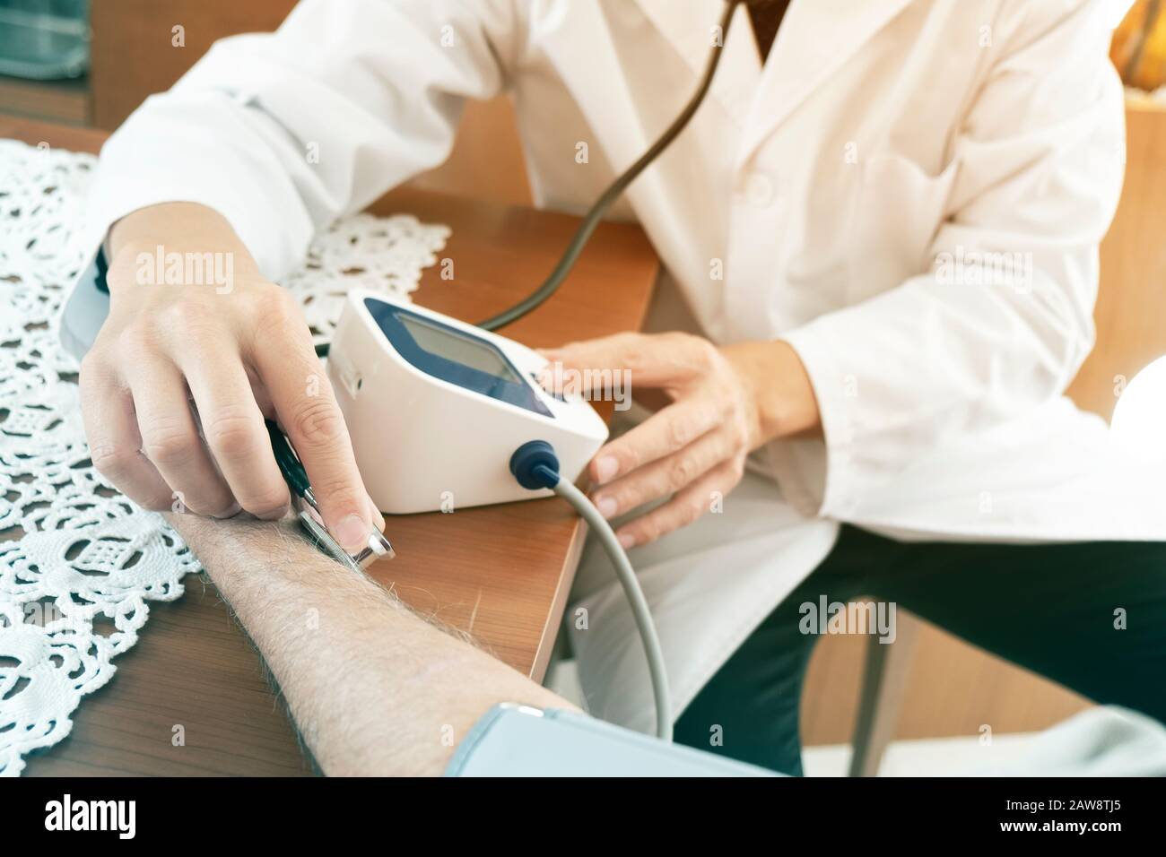 closeup di un medico caucasico, in una mano bianca, che misura la pressione sanguigna di un uomo caucasico anziano con uno sfigmomanometro, a casa sua o a Foto Stock
