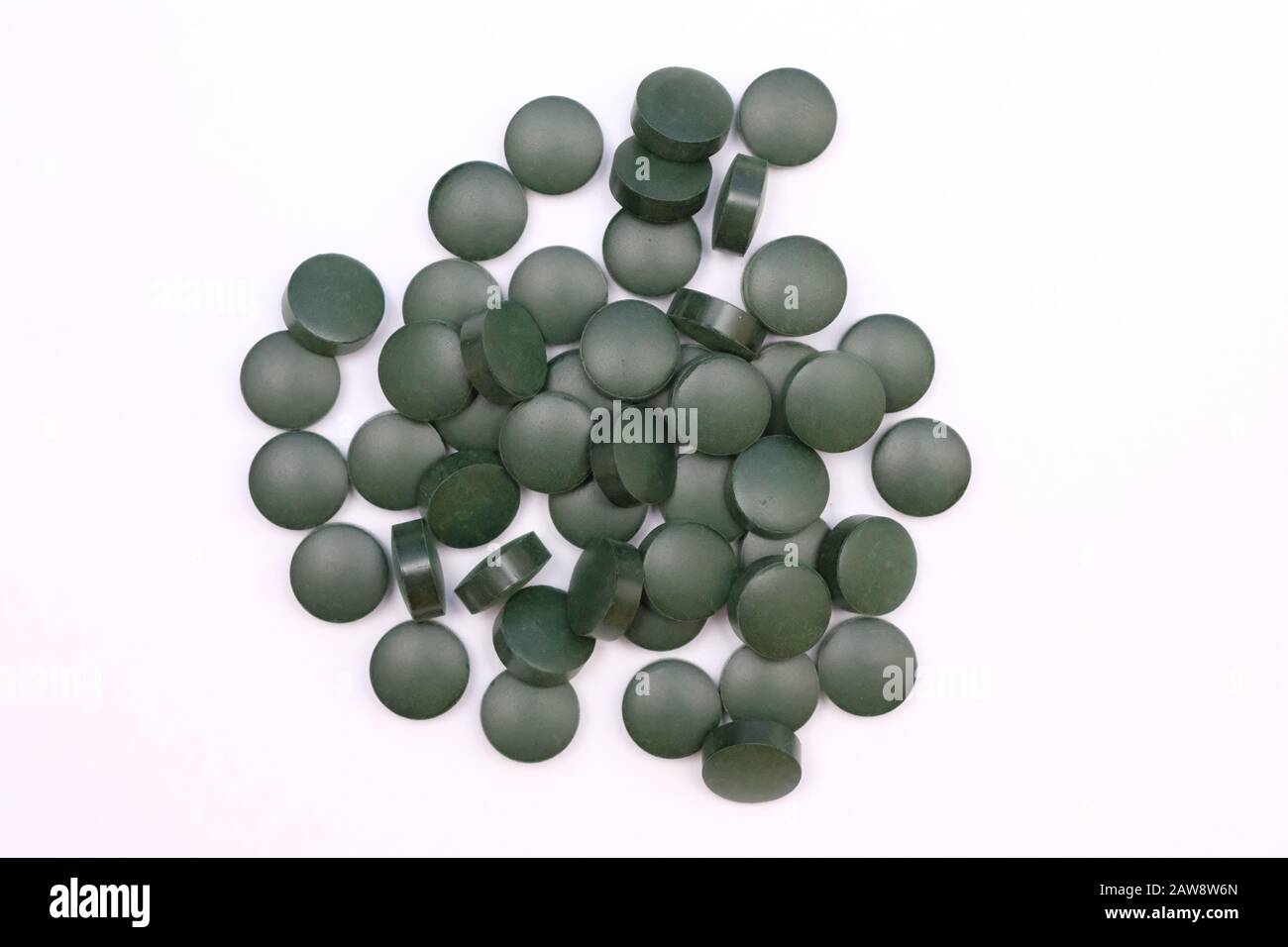 Green round pills vista dall'alto su uno sfondo bianco. Spirulina compresse, integratori alimentari utili. Foto Stock