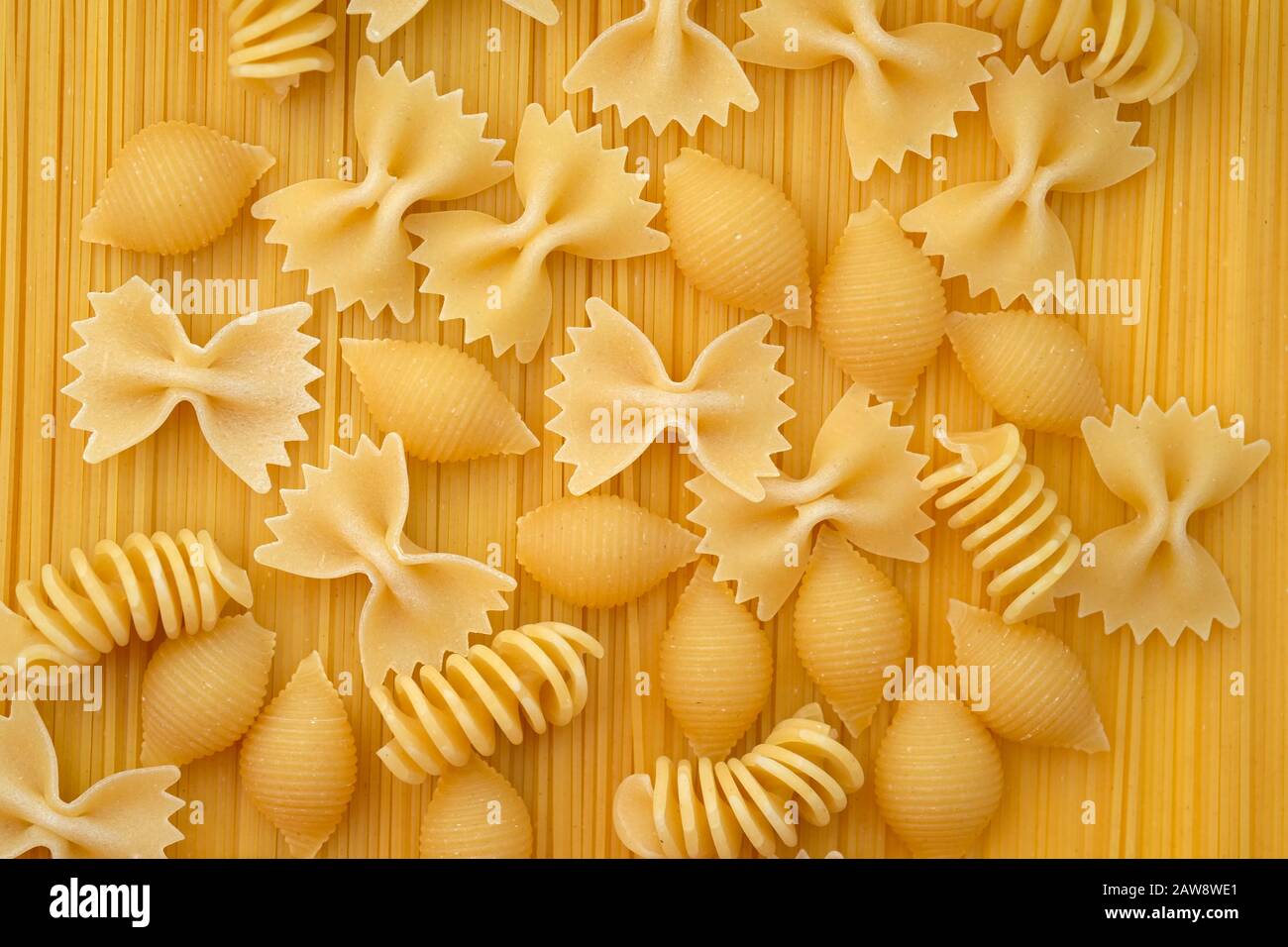 Maccheroni closeup vista dall'alto. Il disco di pasta di diverse forme, archi, spirali e gusci su uno sfondo di spaghetti. La pasta. Foto Stock