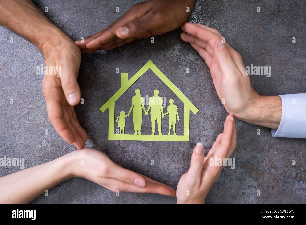 Vista Ad Angolo Elevato Delle Mani Della Persona Che Protegge La Casa Della Famiglia Sul Tavolo Foto Stock