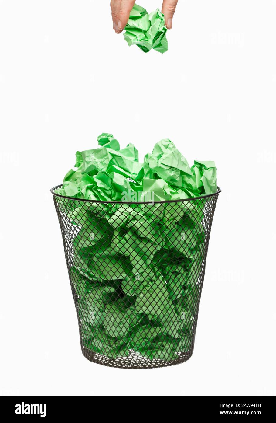 Riciclaggio a mano di carta di spreco verde che cade figliata in un cestino di carta di spreco Foto Stock