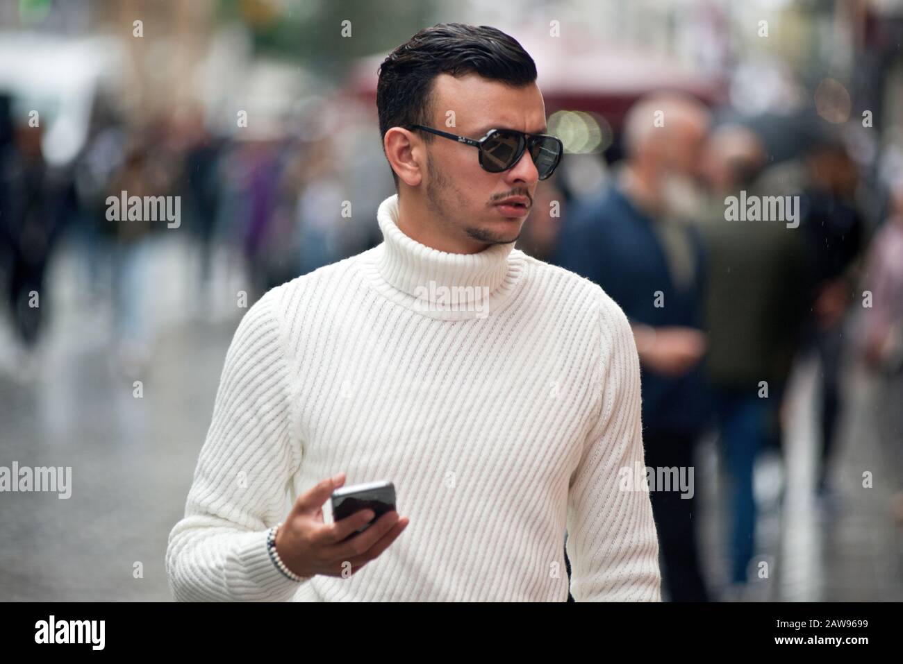 Istanbul: Un giovane uomo con occhiali da sole e un cellulare a piedi su viale Istiklal. Turchia Foto Stock