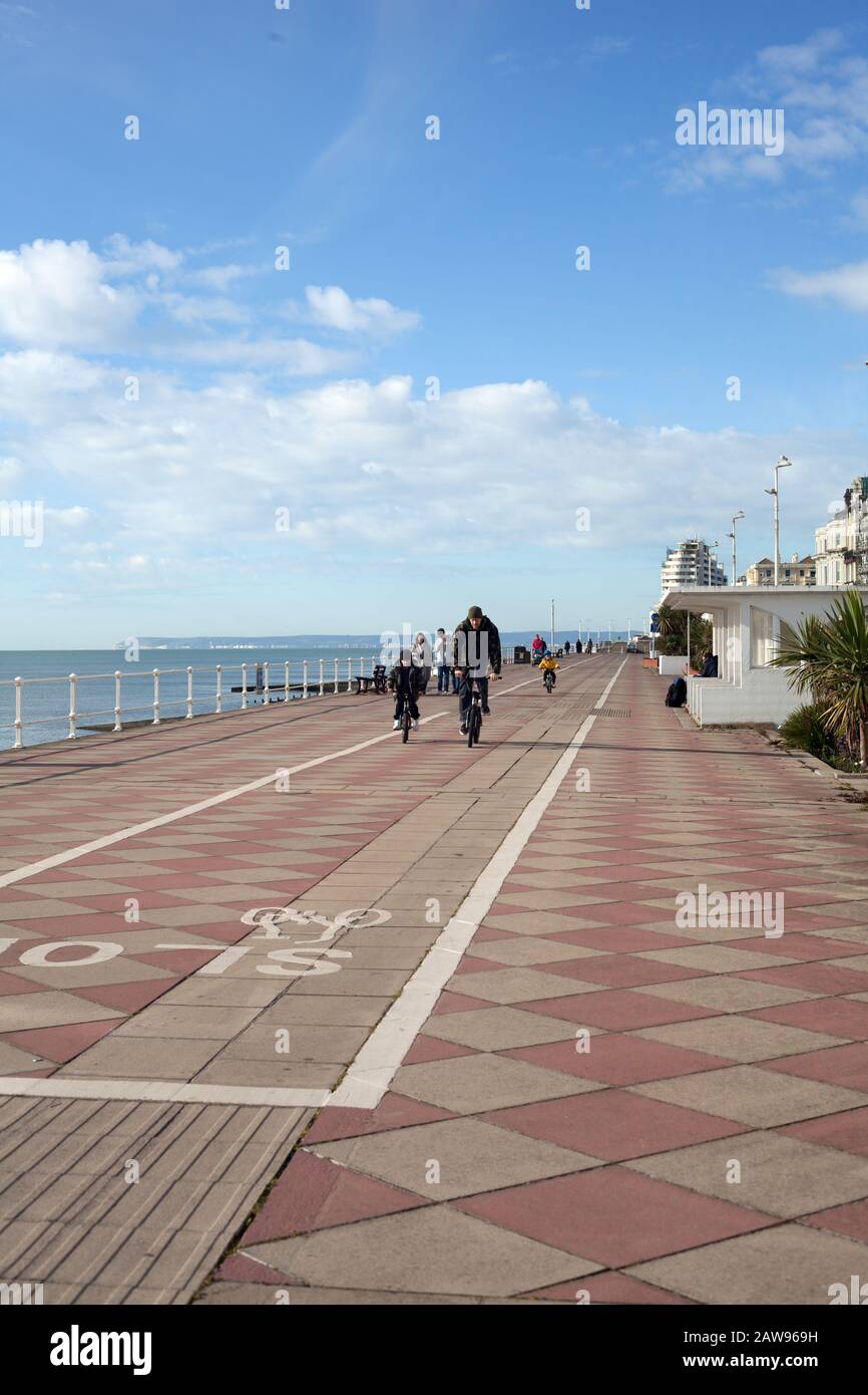 Padre e figlio pedalano lungo la pista ciclabile dedicata lungo il lungomare tra St Leonards on Sea e Hastings, East Sussex, Regno Unito Foto Stock