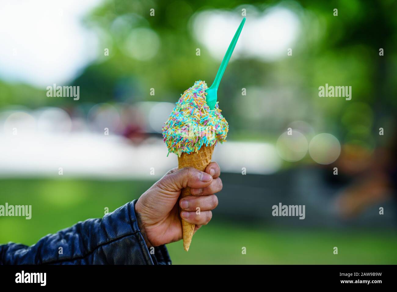 Uomo che tiene il cono del gelato. Particolare di gelato con Rainbow Sprinkles in mano Foto Stock