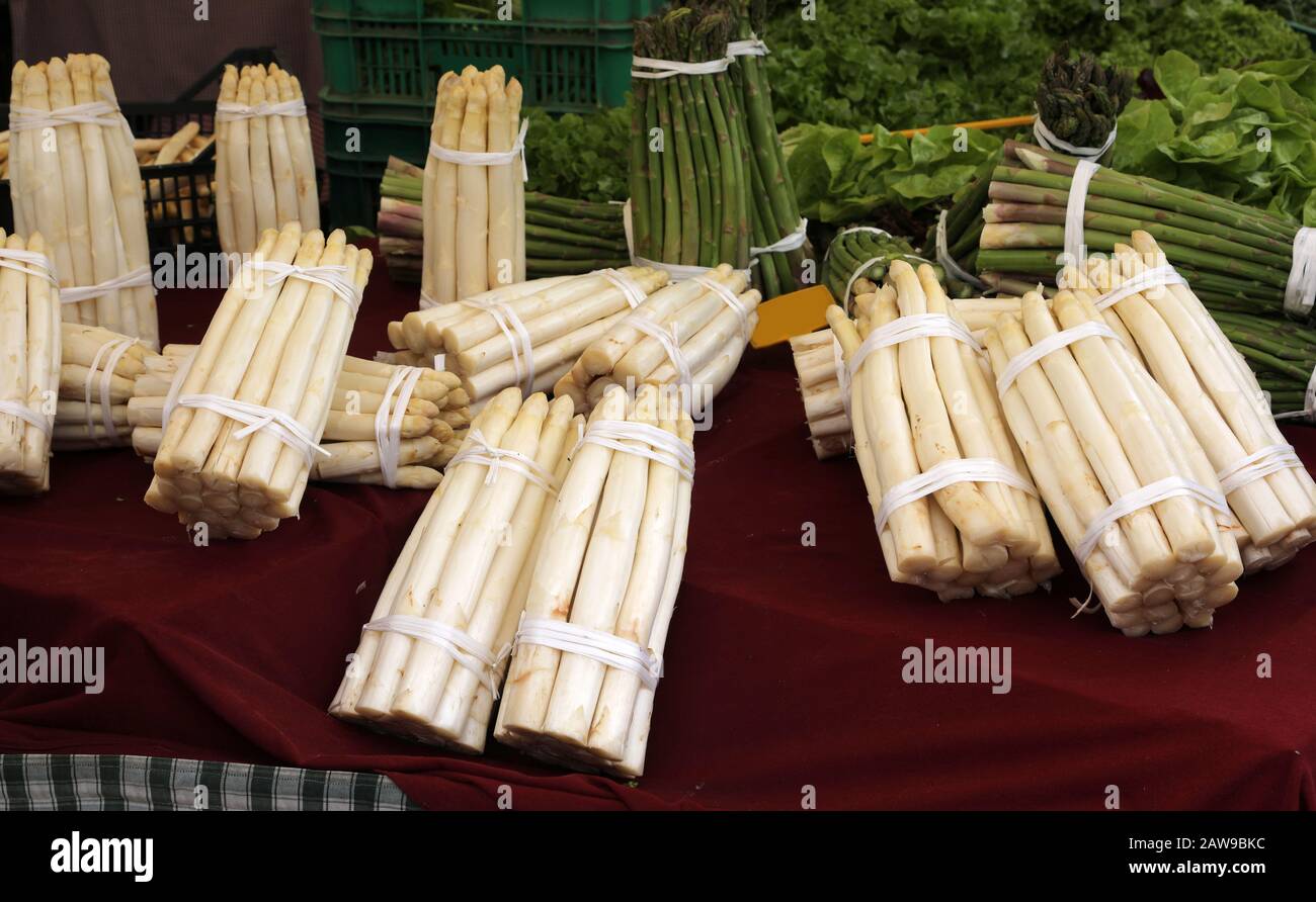 grappoli di asparagi bianchi e verdi in vendita in una stalla di mercato vegetale Foto Stock