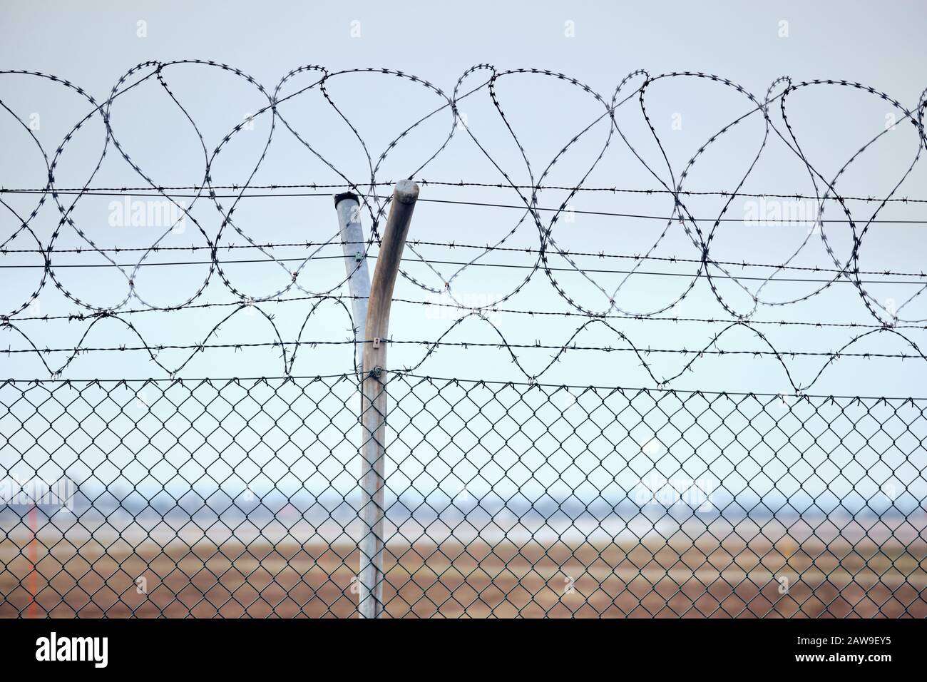 Alto collegamento a catena recinzione con filo spinato in cima a proteggere un aeroporto. Foto Stock