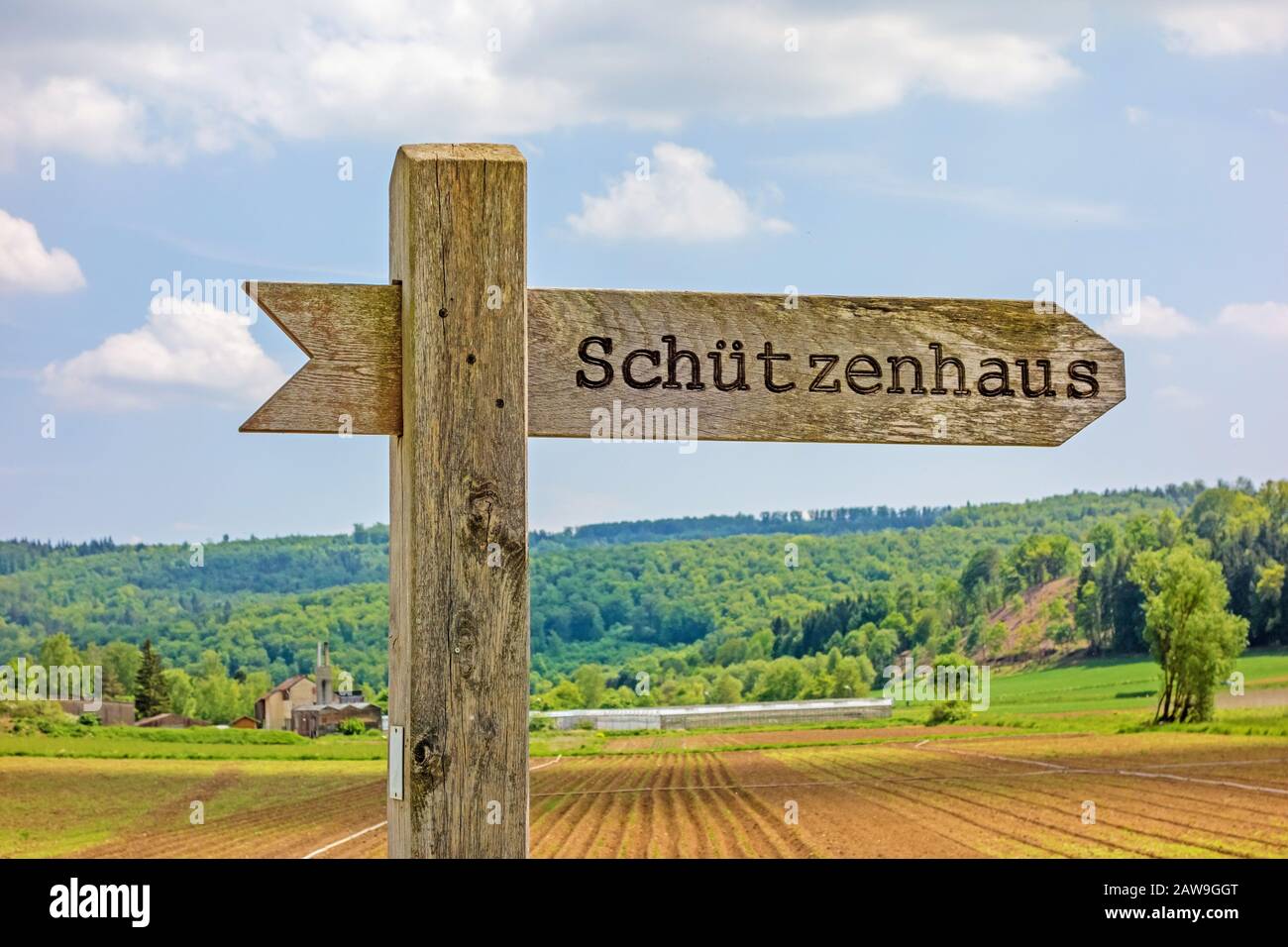 Cartello etichettato con la clubhouse dell'associazione del fucile - in lingua tedesca (Schuetzenhaus) - paesaggio rurale sullo sfondo Foto Stock
