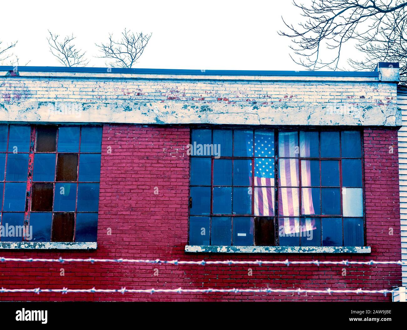 Bandiera americana appesa nella finestra di fabbrica chiusa a Ludington, Michigan, Stati Uniti Foto Stock