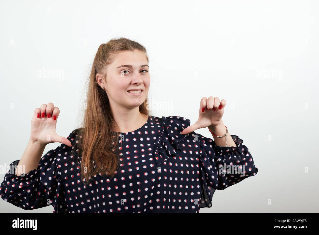 ragazza in un abito nero con cerchi bianchi umore negativo postato pollici giù Foto Stock