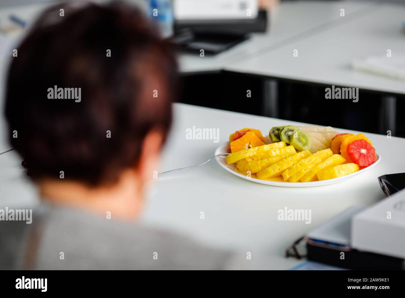 Immagine con profondità di campo bassa (fuoco selettivo) con vari frutti tagliati in pezzi su una piastra su un tavolo bianco. Foto Stock