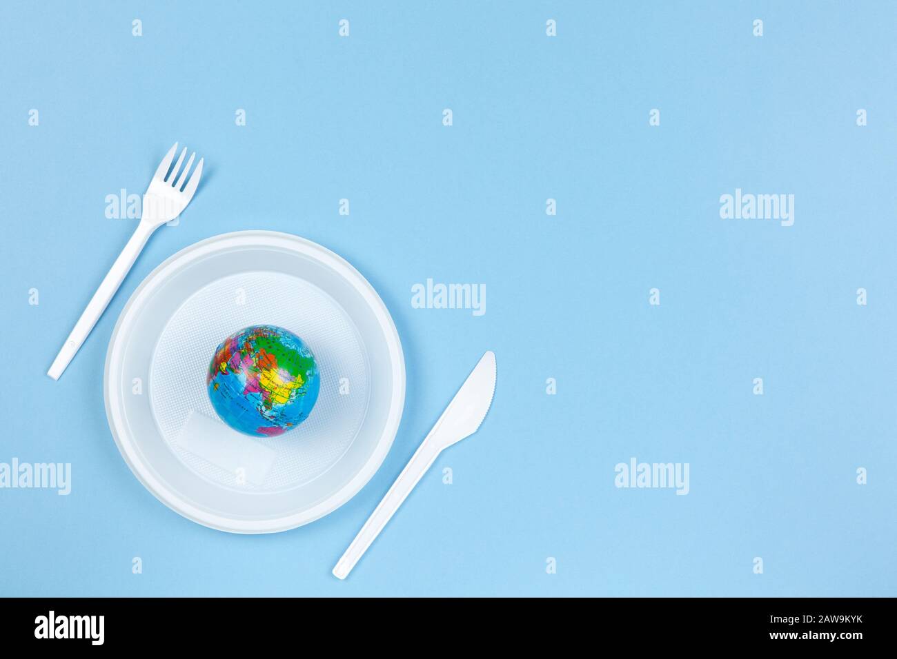 Mosca / Russia - 24 gennaio 2020: Globo piccolo su piastra di plastica usa e getta, forchetta e coltello su sfondo blu, copia spazio. Inquinamento ambientale, re Foto Stock