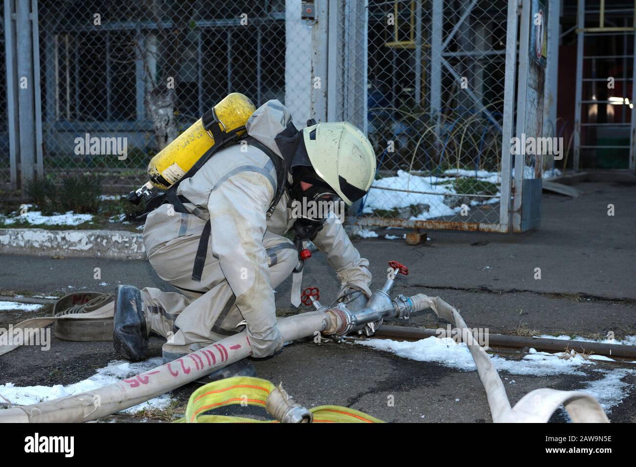 Il soccorritore deve indossare i guanti protettivi che rivolgendo una valvola di un idrante antincendio al territorio degli impianti idrici Foto Stock