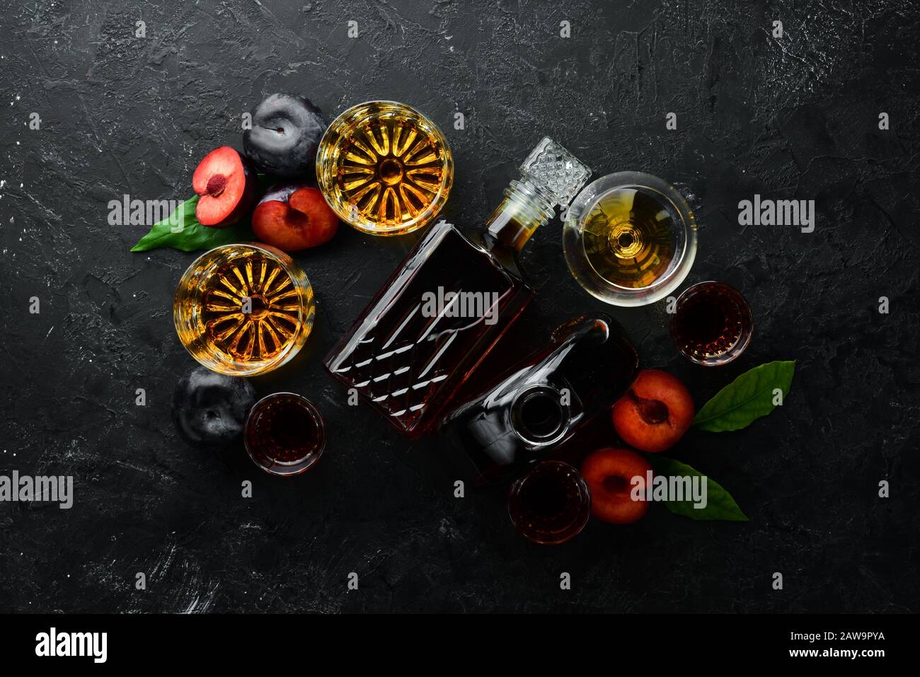 Slivovica - vodka prugna, brandy prugna in una bottiglia su un tavolo di pietra nera. Bicchieri con bevande alcoliche. Vista dall'alto. Spazio libero per il testo. Foto Stock