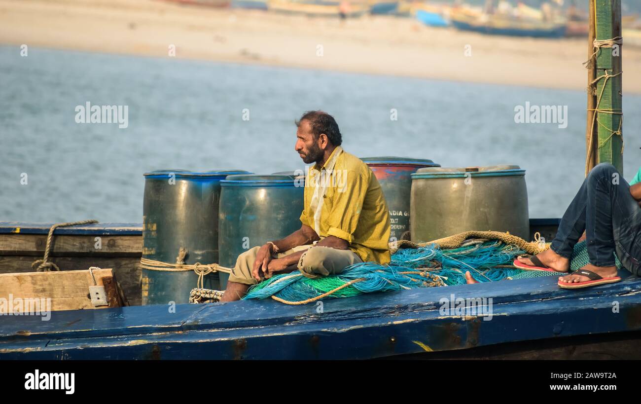 Un pescatore siede nella sua barca da pesca per andare a pescare in mare al largo del porto dell'isola di Diu in India. Foto Stock