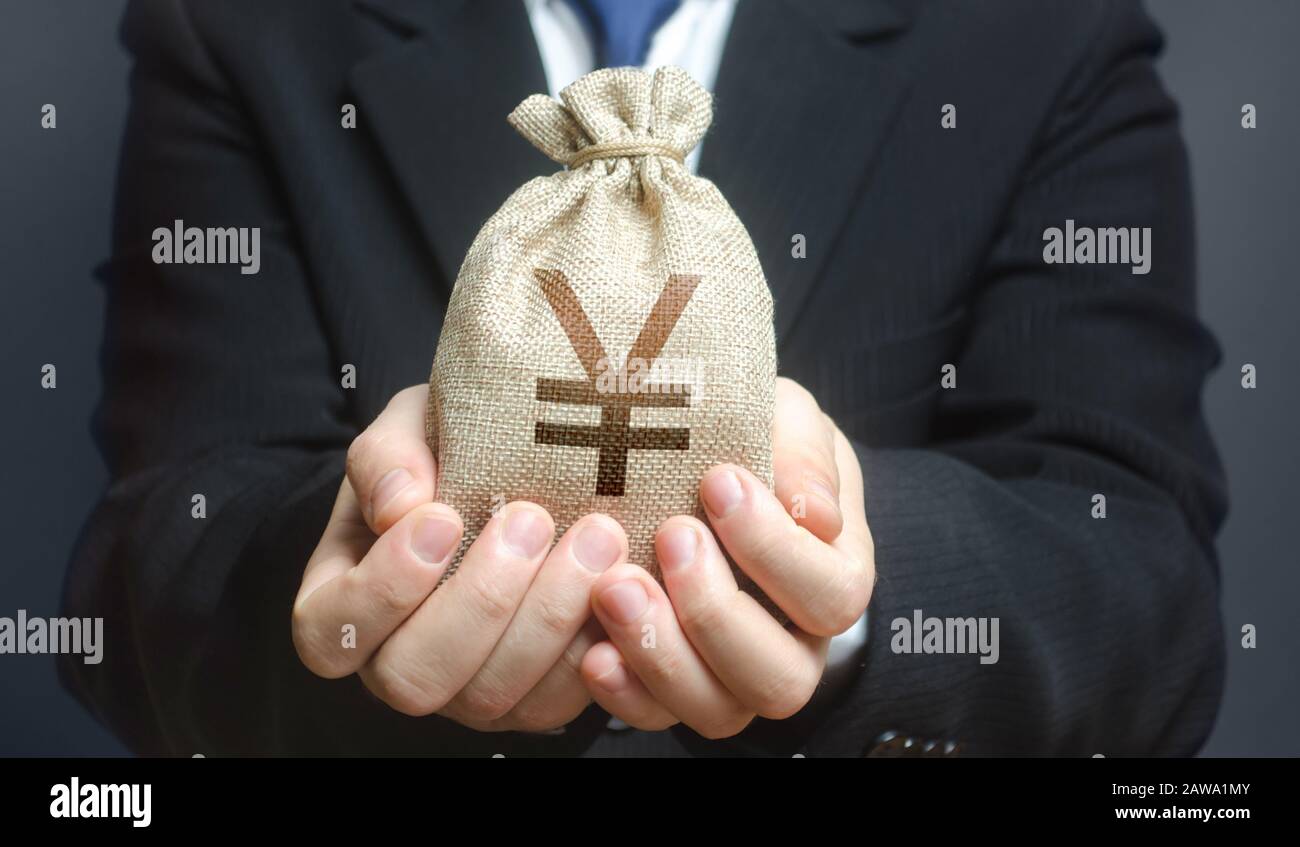 Un uomo tiene fuori una borsa di soldi di Yen yuan. Commercio, economia. Concessione di finanziamento di progetti di imprese o di istruzione. Credito di prestito finanziario di cassa di disposizione. Banca d Foto Stock