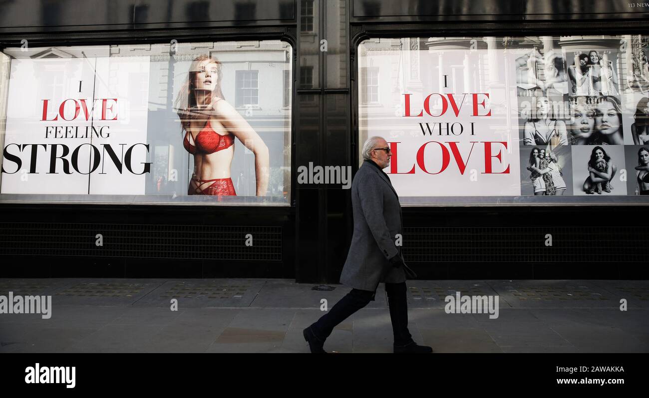 Un uomo passa davanti a una vetrina con un cartello che dice "MI PIACE SENTIRE FORTE" e "MI PIACE CHI MI PIACE" davanti a San Valentino. Foto Stock