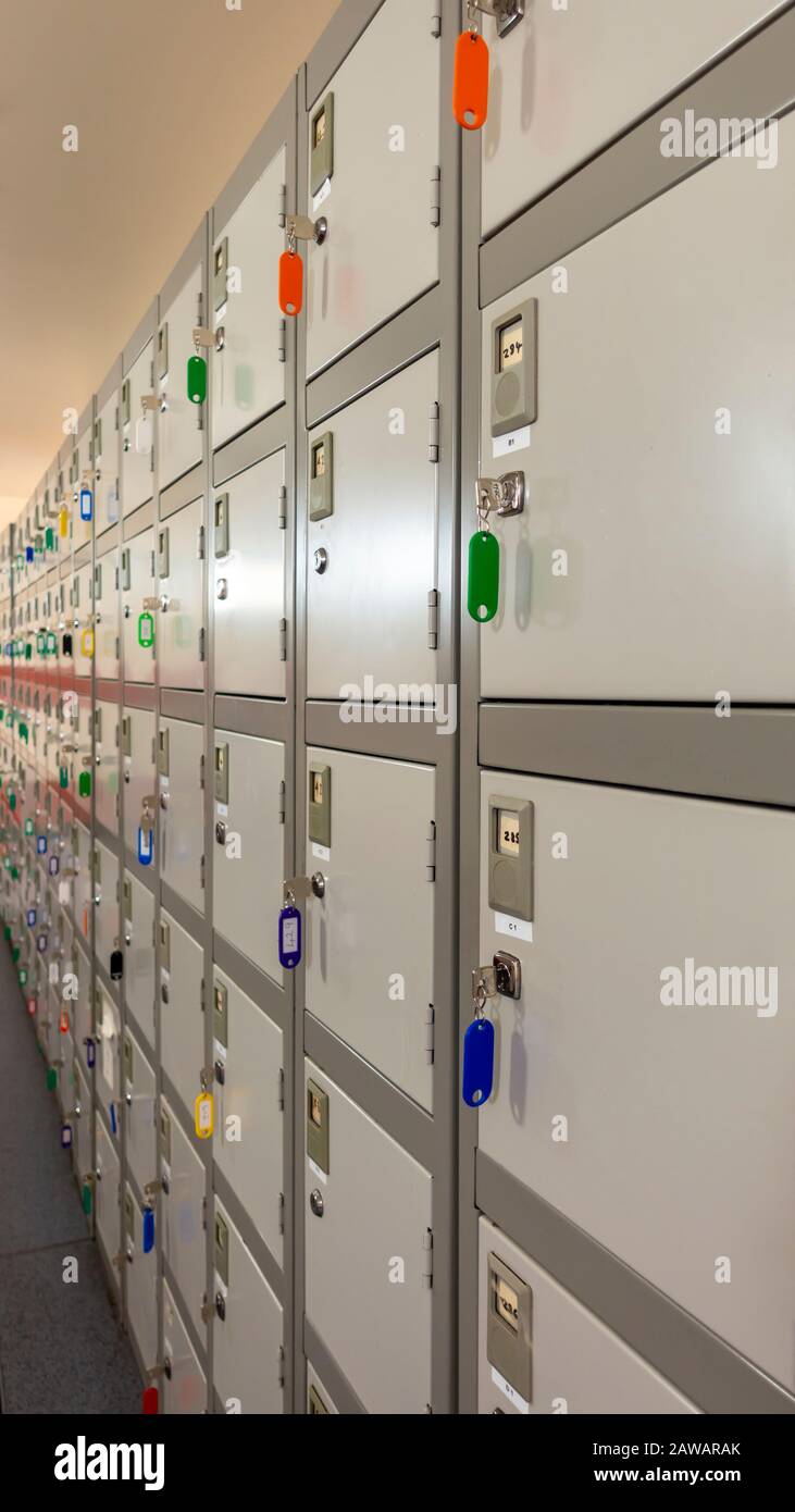 Fila di piccoli armadietti personali industriali con le loro chiavi appese in un corridoio di magazzino Foto Stock