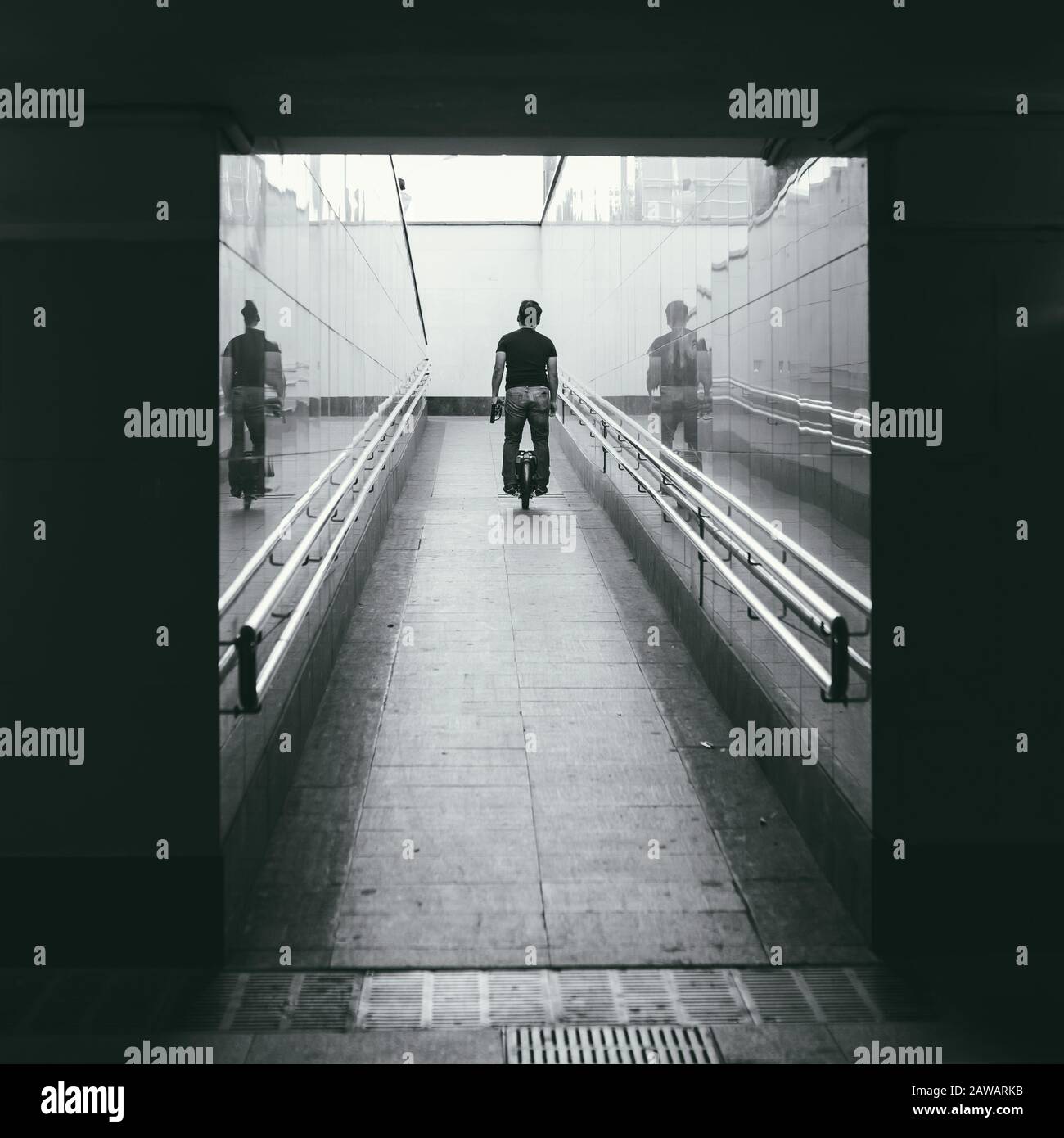 un uomo di mezza età non identificato corre un monociclo su una rampa nel sottopassaggio. Vista posteriore. Trasporto personale del futuro. Immagine in bianco e nero Foto Stock