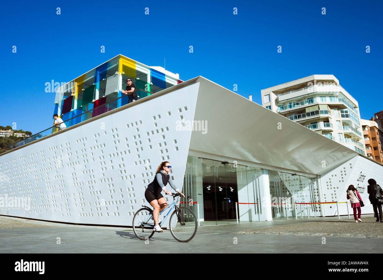 Malaga, Spagna : una giovane donna passa in bicicletta oltre il museo d'arte moderna del Centre Pompidou di Malaga inaugurato nel 2015. Foto Stock