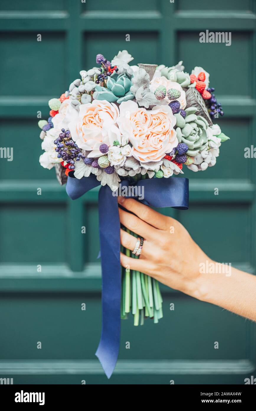 Fiori fatti a mano in argilla polimerica giapponese. Assomiglia ad un mazzo di nozze reale. Sullo sfondo di una porta di legno verde Foto Stock