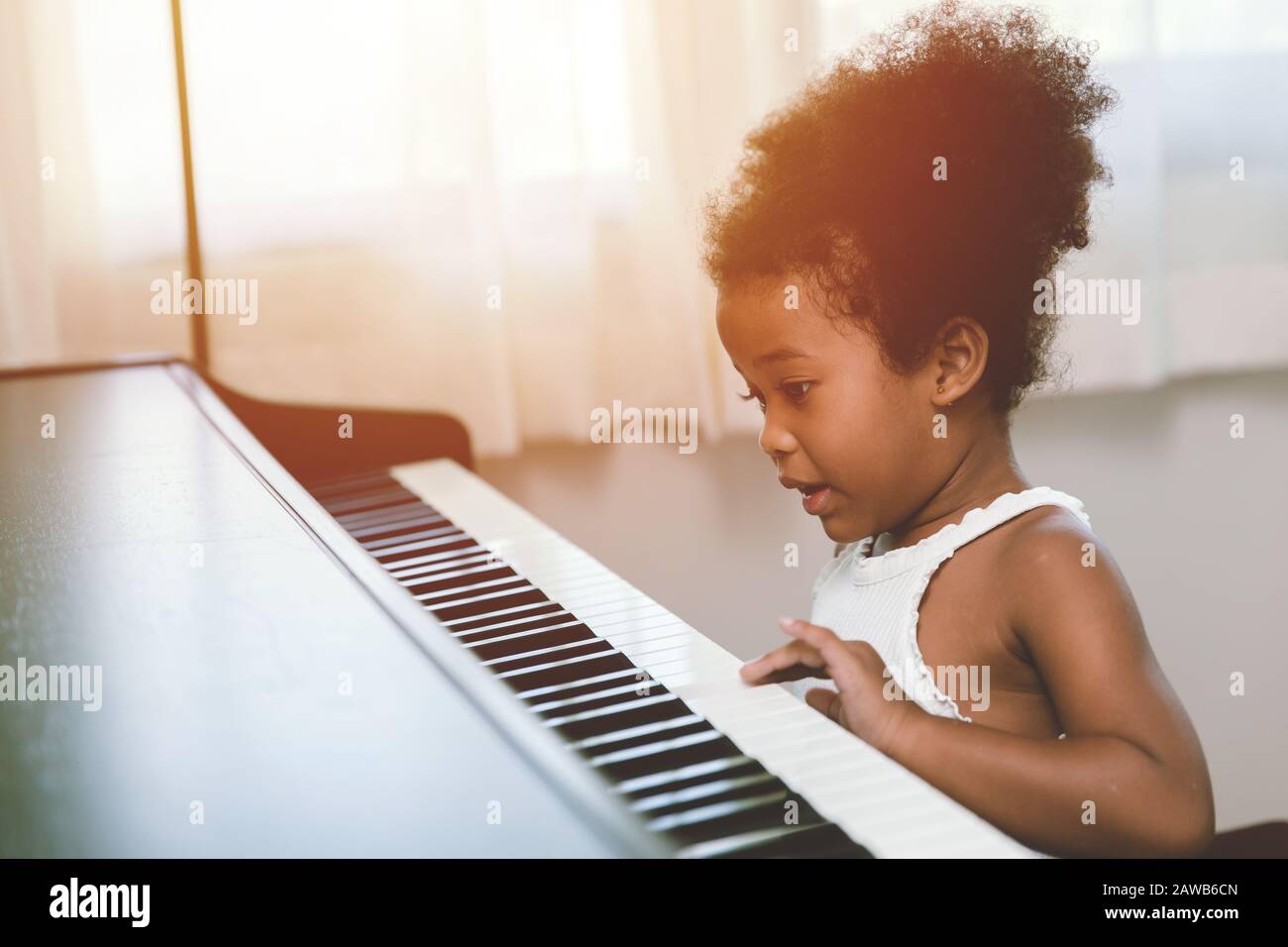 bambina che suona il pianoforte che guarda emozionante felice e godere con strumento musicale e essere giocatore Foto Stock