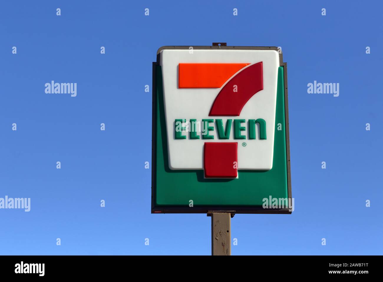 Un 7-Eleven segno su una pole contro un cielo soleggiato e blu Foto Stock