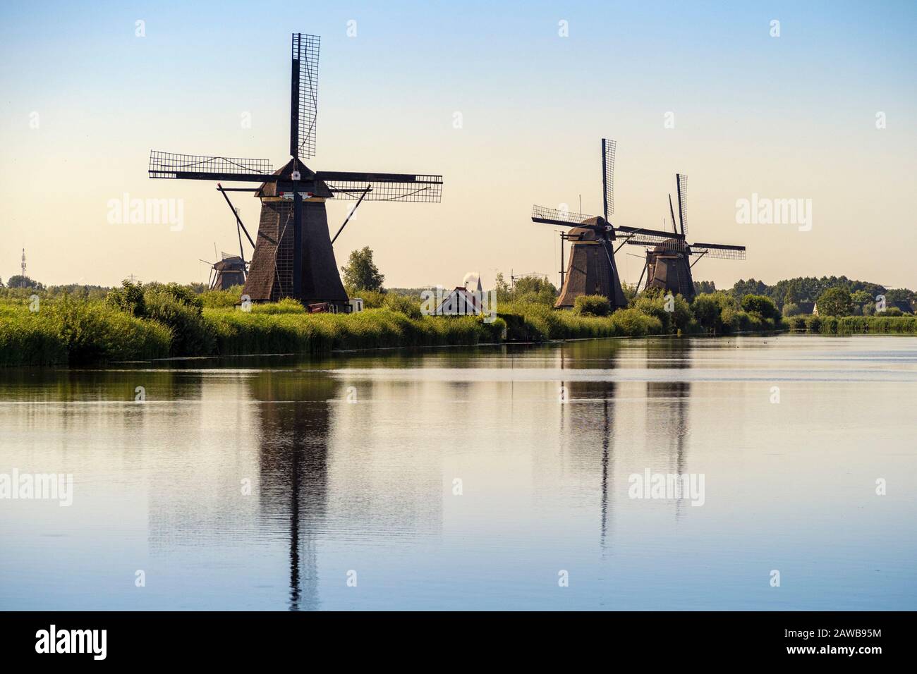 KINDERDIJK, PAESI BASSI - 04 LUGLIO 2019: Gli storici mulini a vento del 17th ° secolo a Kinderdijk alla luce del mattino presto con riflessione in un canale Foto Stock