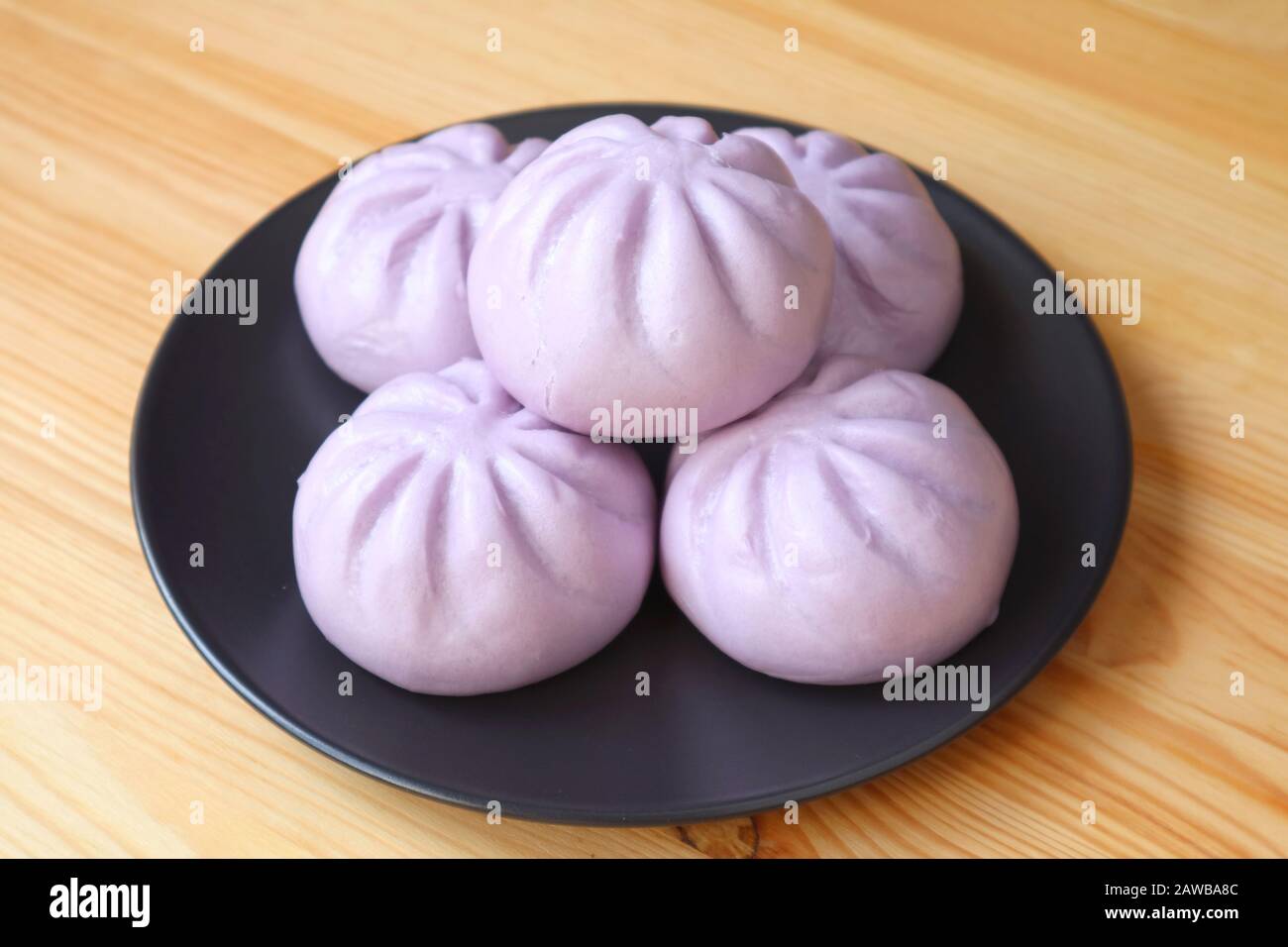 Piatto di molti panini al vapore di patate dolci viola serviti su tavola di legno Foto Stock