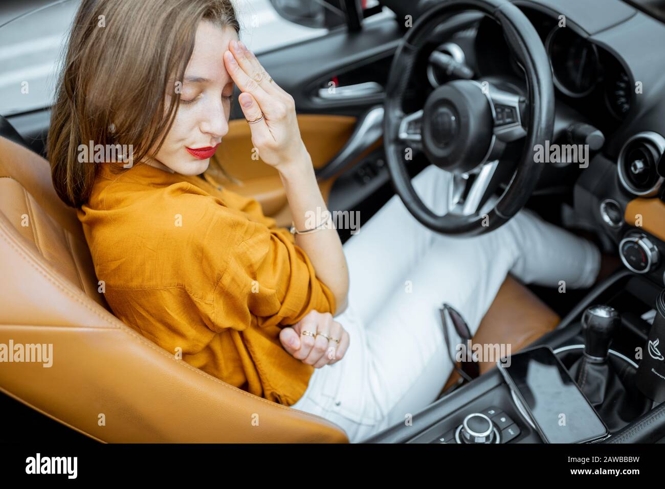 Giovane donna sensazione di stress, avendo un mal di testa mentre seduto sul sedile del conducente di auto convertibile Foto Stock