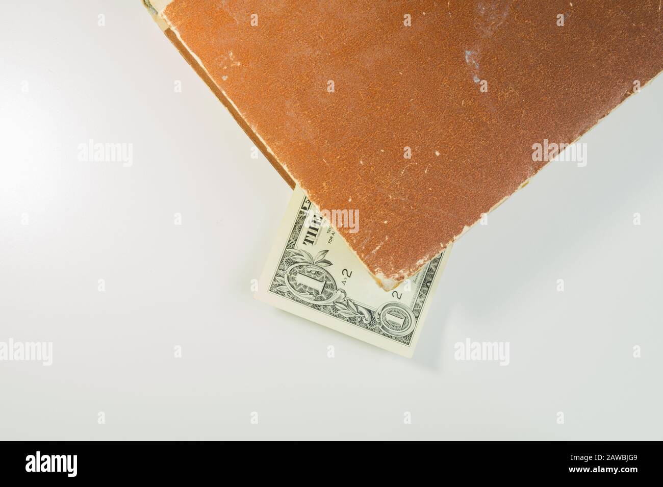 Soldi in un libro. Dollaro fattura usato come un segnalibro nel libro su uno sfondo bianco. Copia spazio Foto Stock