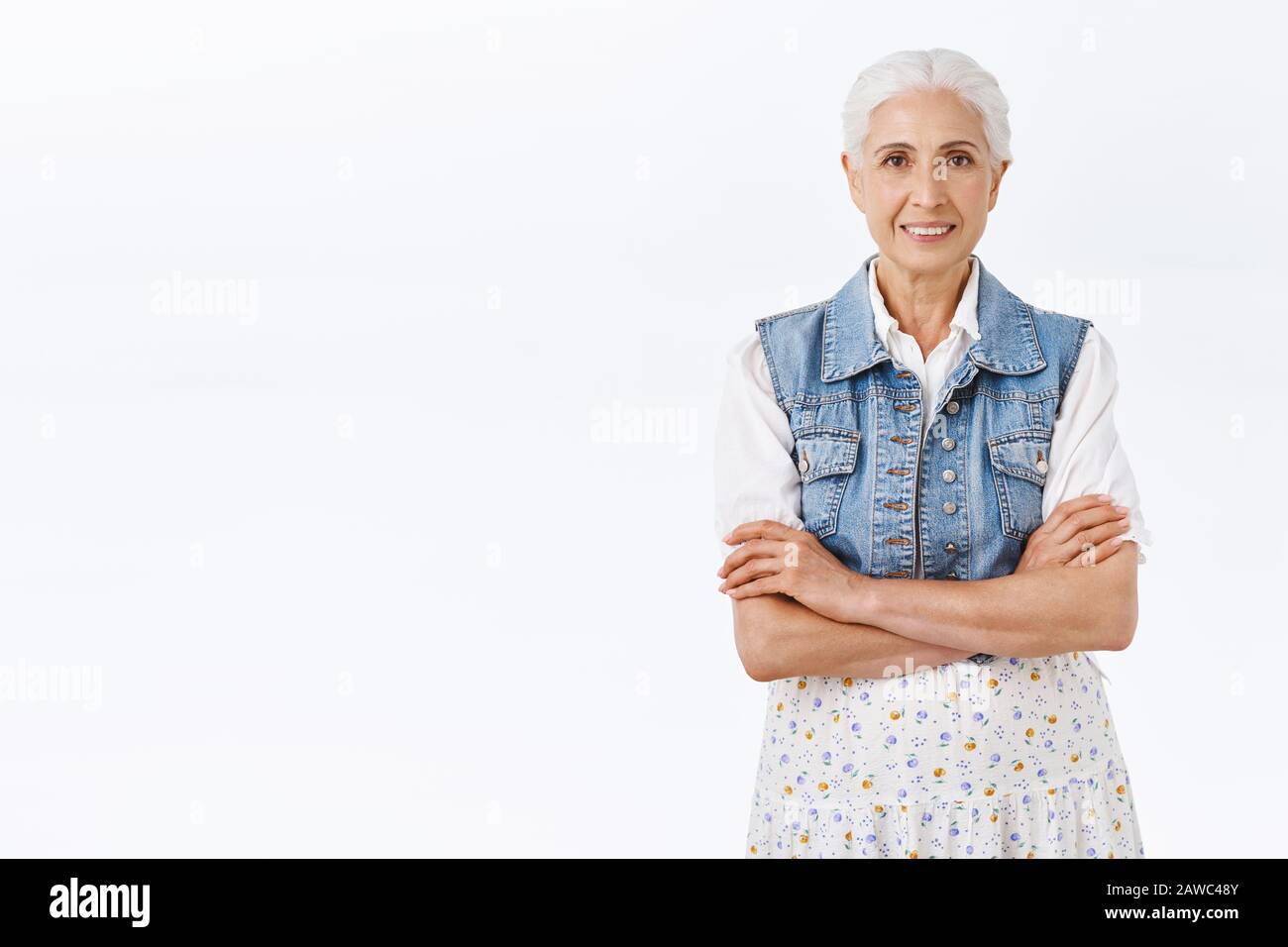 Felice sorridente vecchia donna con capelli bianchi pettinati, indossando elegante vestito moderno, croce mani sul petto, grinning gioiosamente, esprimere positività e. Foto Stock