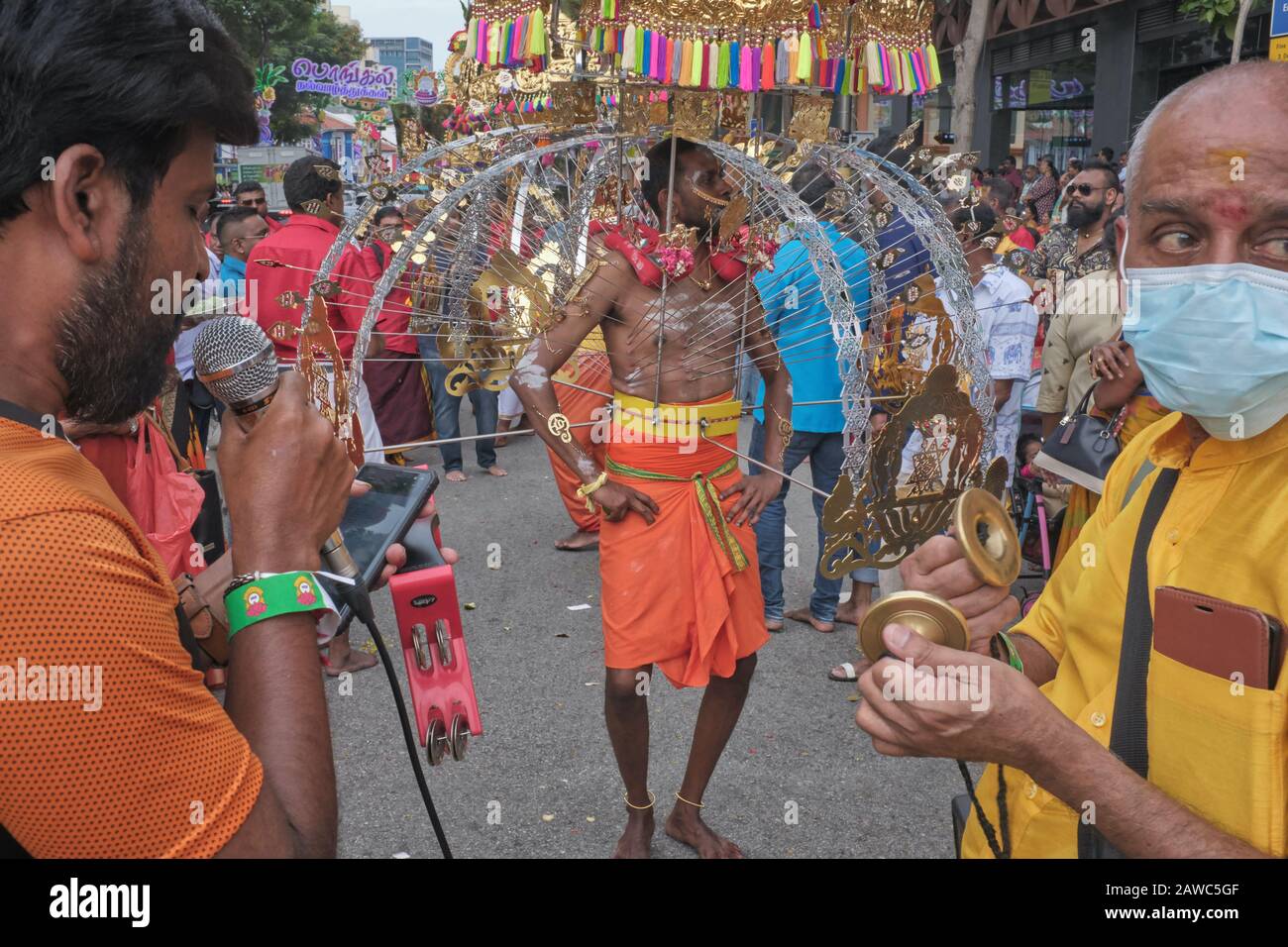 Per il festival indù di Thaipusam, un partecipante sta portando un Kavadi in onore di dio Murugan, accompagnato da famiglia e amici; Little India, Singapore Foto Stock