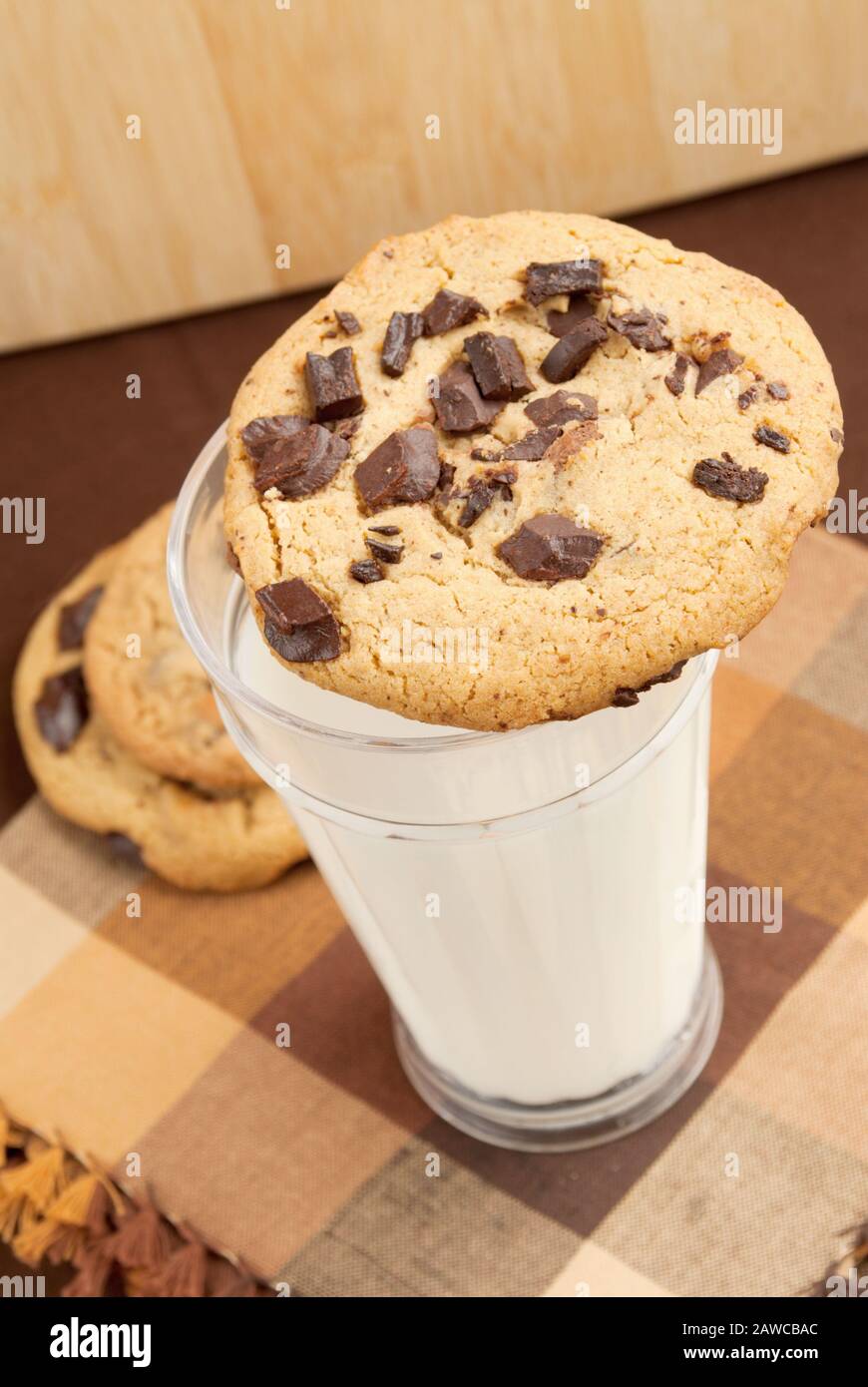 Biscotti fatti in casa con pezzetti di cioccolato sulla parte superiore di un bicchiere di latte bianco freddo. Messa a fuoco selettiva. Foto Stock