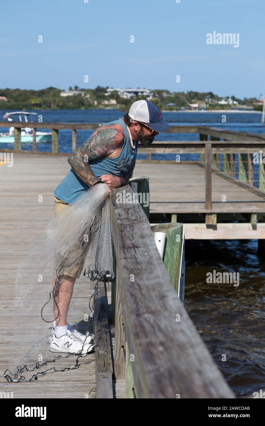 Un pescatore tatuato si prepara a gettare la sua rete nella tasca del Manatee al Sandsprit Park di Port Salerno, Florida, USA. Foto Stock