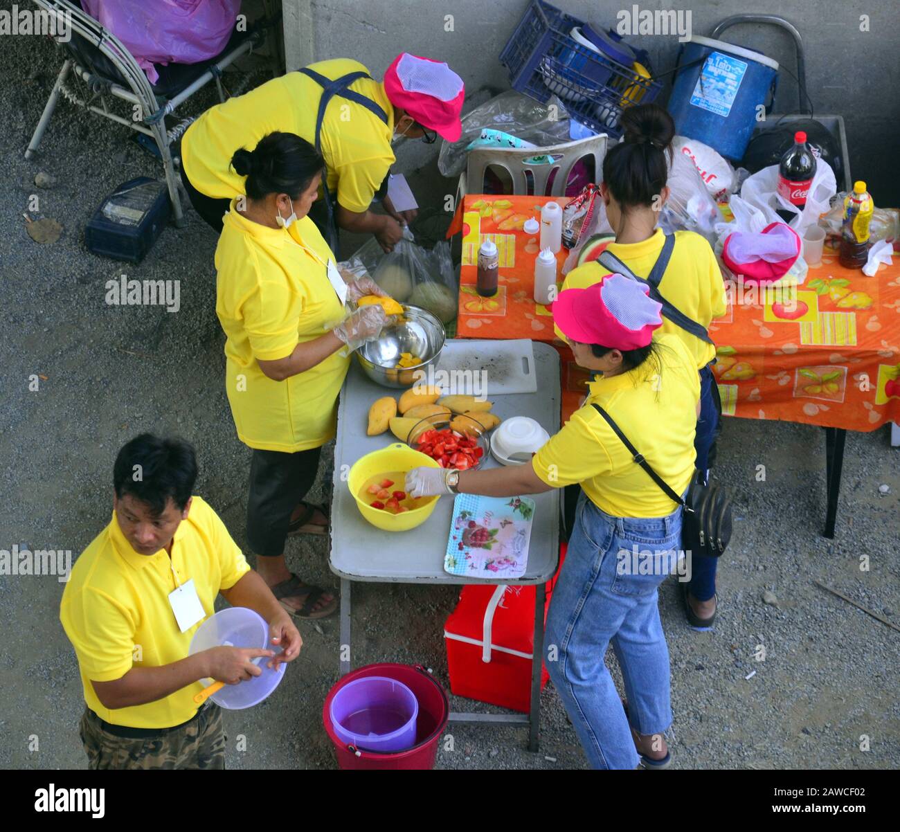 Una vista dall'alto di uomini e donne in magliette gialle che preparano il cibo a un evento all'aperto a Bangkok, Thailandia, Asia Foto Stock
