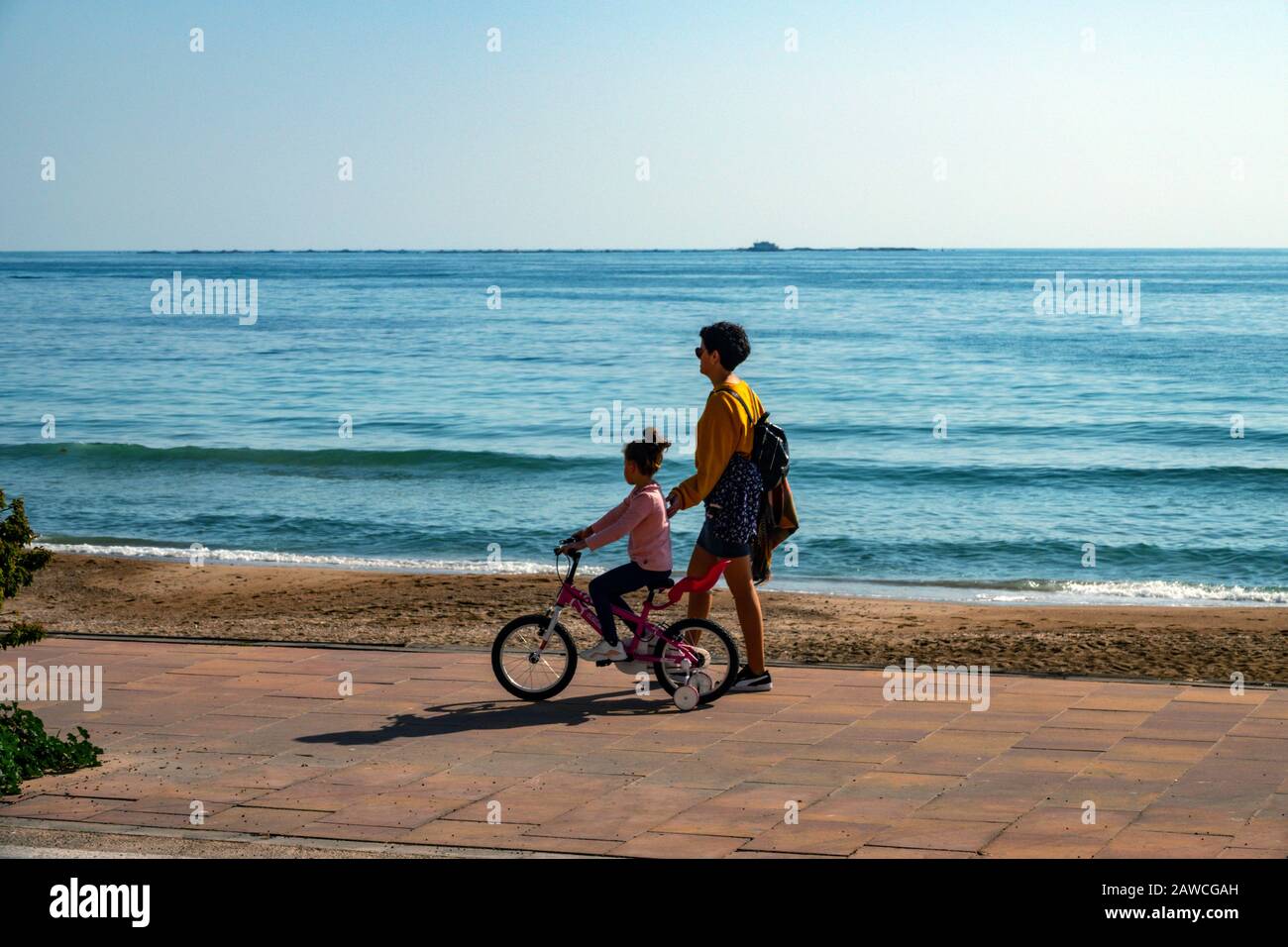 Madre e bambino in bicicletta, a piedi sul lungomare, Vilajoyosa, Villajoyosa, Alicante, Costa Blanca, Spagna Foto Stock
